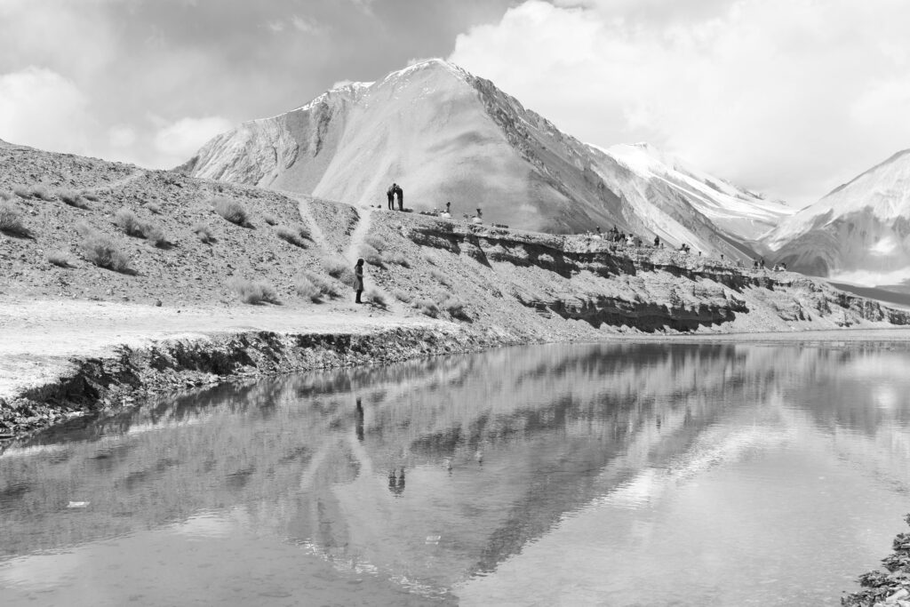 Grayscale Photo Of Mountain Near Body Of Water