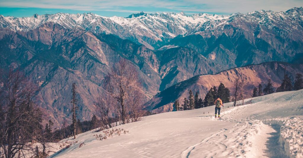 A Person with Back Pack Walking on Snow Covered Mountain